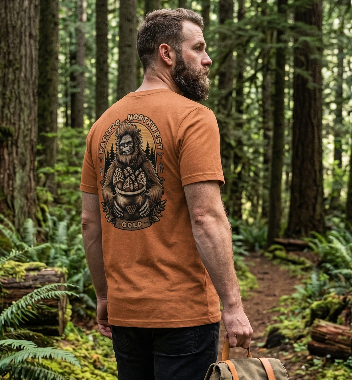 Man walking through a forest wearing a Bigfoot PNW Gold t-shirt.