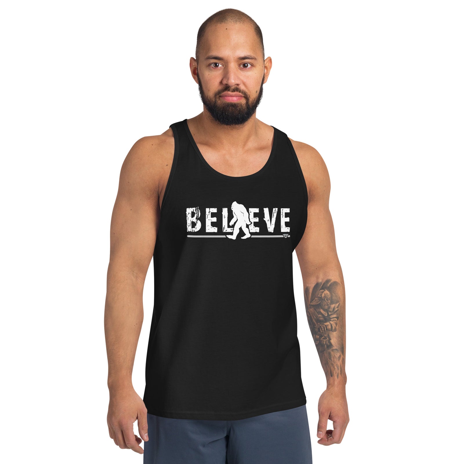 Man wearing a black Bigfoot themed tank top with 'BELIEVE' and a graphic design on a white background