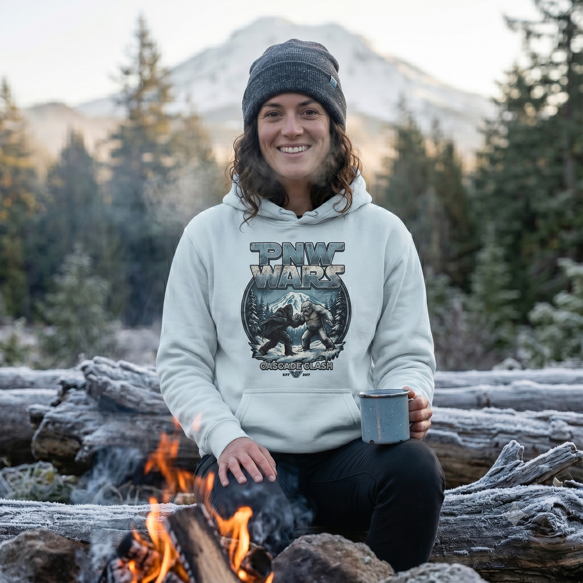 Person wearing a blue PNW Wars hoodie, sitting by a campfire in a forest setting.