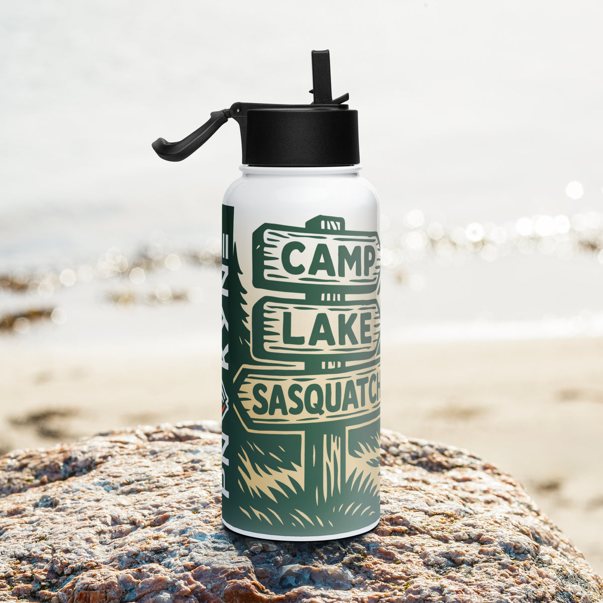 Water bottle with Bigfoot camping-themed design featuring a sign post pointing towards Camp, Lake, and Sasquatch, on a rock by the beach.