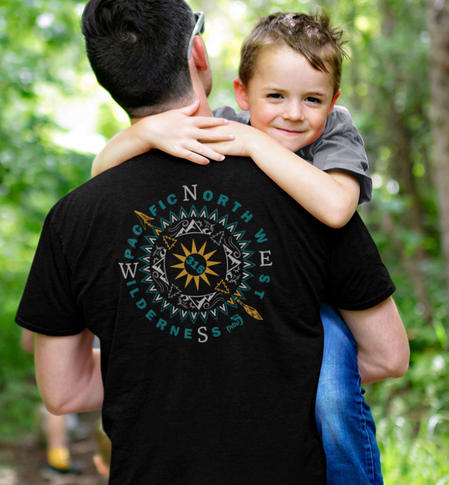 PNW Sun Peaks Compass Short Sleeve Shirt on a man who is holding a child