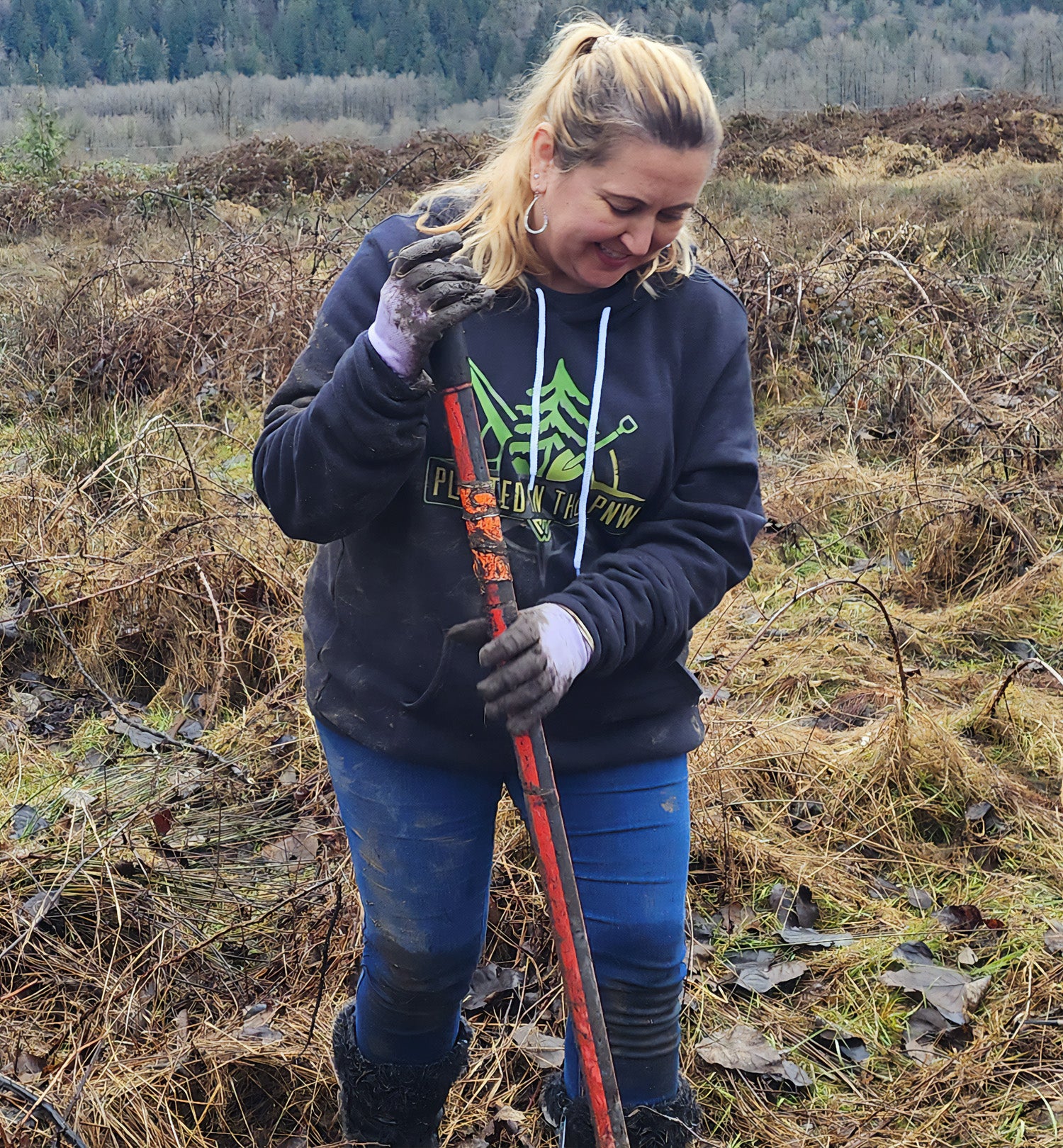 Woman wearing a Planted in the PNW Pullover hoodie while planting trees