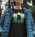 Woman wearing Social Distance Master Short Sleeve Bigfoot Shirt and a jacket in the PNW woods